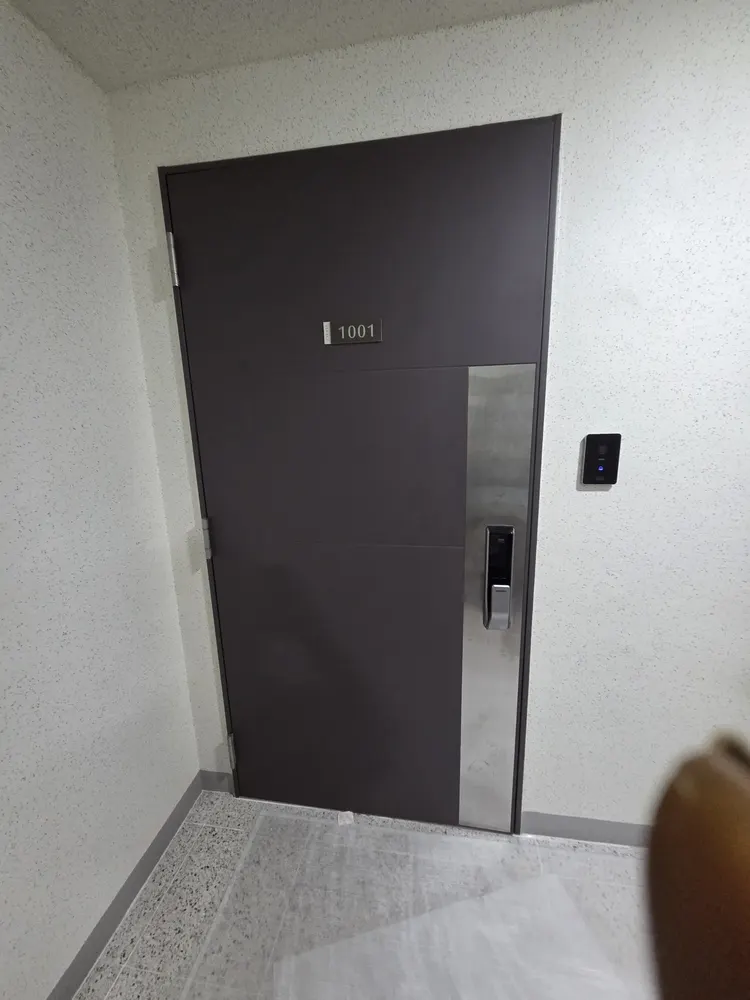 현관문 도어클로저 조정 나사를 조절하는 작업 장면